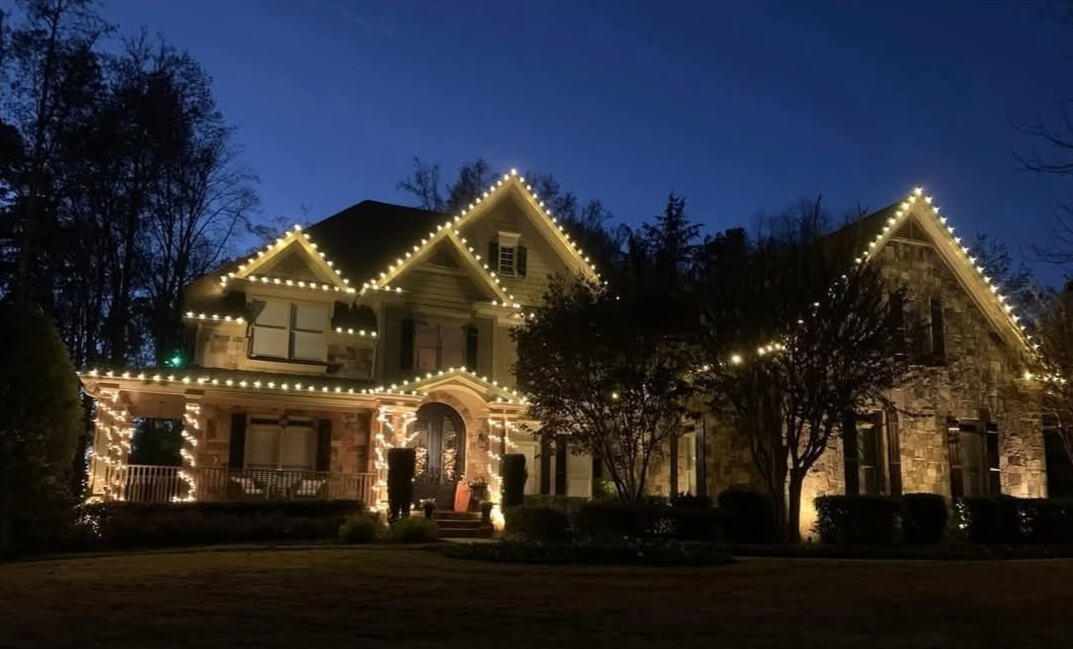 Stone home with warm white C9 Christmas lights outlining every gable