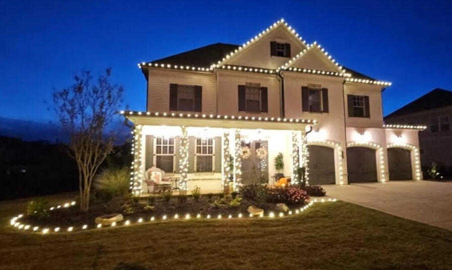 Residential Christmas lights on a two-story home roofline, porch columns and garage arches